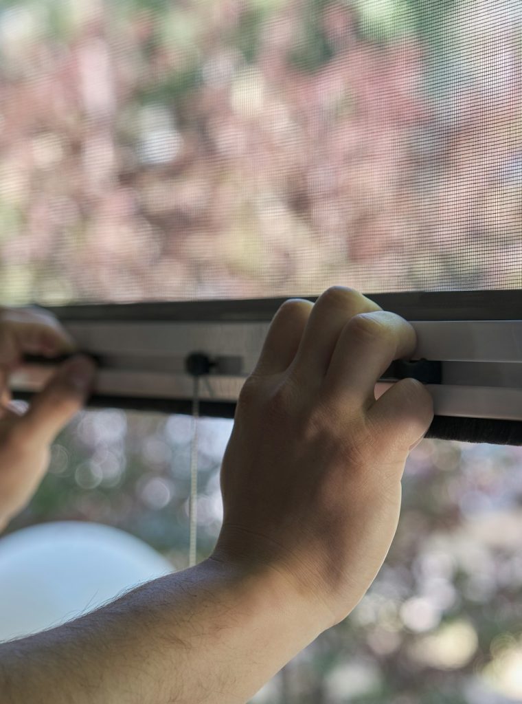 Man hands holding retractable insect screen holder to open or close it.